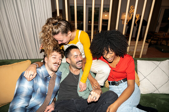 Diverse friends laughing together on couch at home