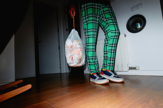 a man carries a tied bag of food waste inside his home