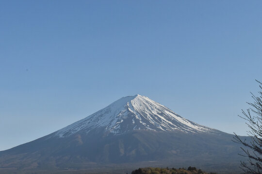 Snowcapped Fuji mountain peak under clear blue sky with calm winter landscape and distant ridge