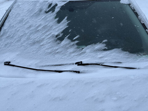 Snow covers car windshield in winter season