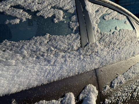 Snow covers a car on a winter morning