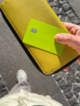 Holding a yellow wallet with a green card nearby
