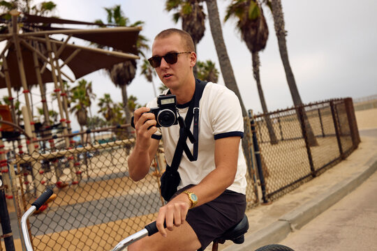 Man Rides a Bike and Taking Photos in Venice Beach