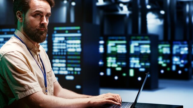 Skilled IT programmer imputing high tech facility hub disaster recovery plan on laptop to provide smooth restoration of service, limiting damage and maximizing operations uptime