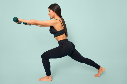 Young latina woman performing lunges with dumbbells