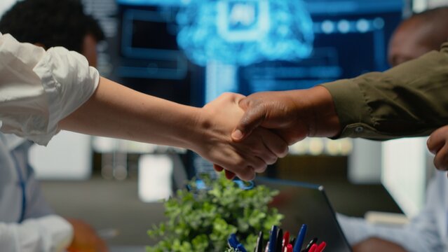 Programmer shaking hand with businessmen in tech agency boardroom. Angel investors meeting with AI startup company CTOs to hear technology presentation before investing, camera B
