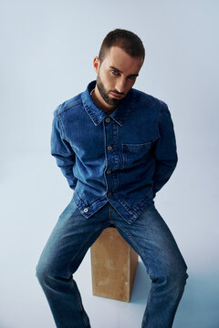 Man Sitting on a Box in a Blue Room Wearing Denim Clothes