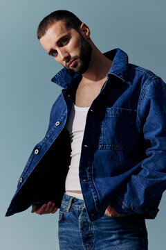 Man Poses in a Denim Outfit Against a Solid Background