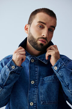 Man Poses in Denim Jacket in Studio Setting With Blue Background