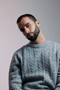 Man Posing Indoors Wearing a Gray Sweater in Soft Lighting