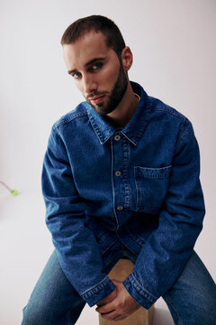 Man Seated on a Stool Wearing Denim Clothing in an Indoor Space