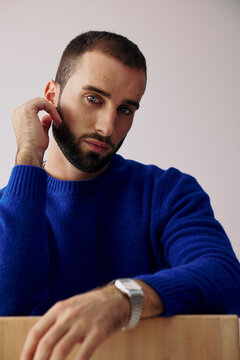 Man Wearing Blue Sweater Posing for a Photo in a Simple Space