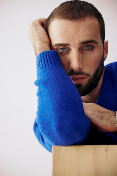 Man in Blue Sweater Resting His Face on His Hand