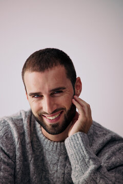 Smiling Man Touches His Cheek in a Simple Setting in Daytime
