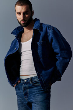 Model Poses in Denim Jacket and Tank Top Against a Gray Background