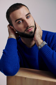 Man Poses With Hands on His Face in a Studio Setting