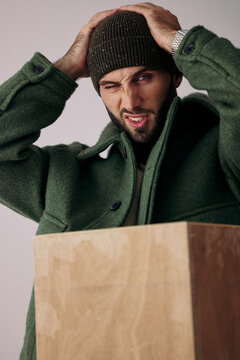Man Showing Frustration While Holding His Head Near a Wooden Box
