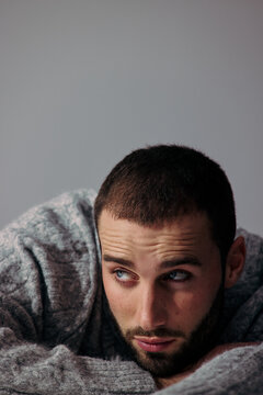 Man in Gray Sweater Looks Away in Indoor Setting