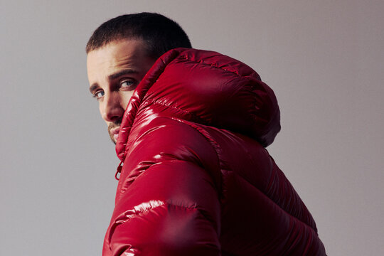 Man Wearing Red Puffer Jacket Looks Over Shoulder in Studio