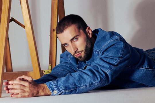 Young Man Stretches on Floor in Denim Jacket During Studio Session