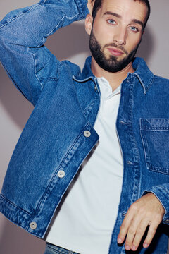 Man Poses in Denim Jacket and Polo Shirt in Studio Setting