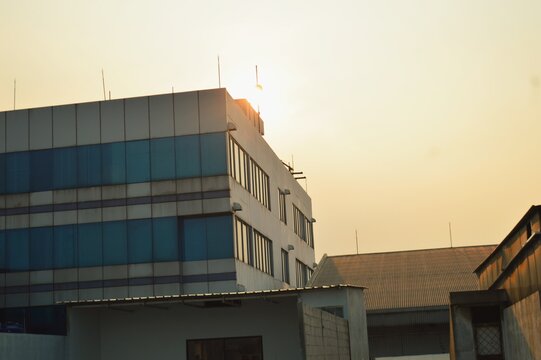 Processed with VSCO with wwf preset
Modern building with glass windows and sunlight at sunset in urban area. Office or industrial architecture with warm golden hour lighting.