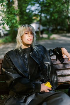Young Person Sits on Bench in Park During Sunny Day