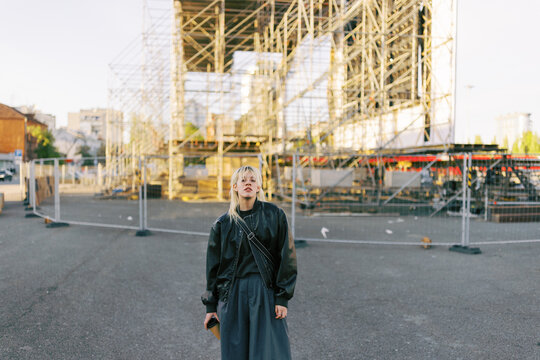 Young Person Stands Near Construction Site in Urban Area