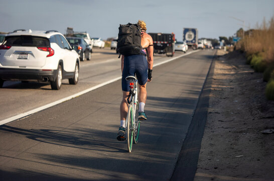 A man riding a ten speed bicycle on a busy freeway . The image is from the Interstate 5 freeway in San Diego County Ca