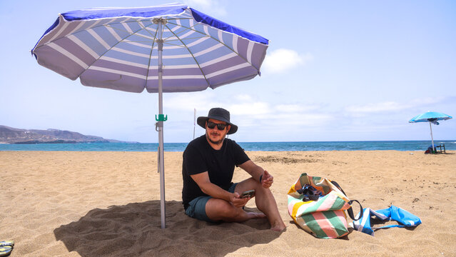 Man Relaxing Under Beach Umbrella on Sunny Day