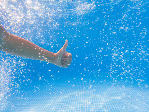 Underwater thumbs up. Hand in a pool showing the international sign.