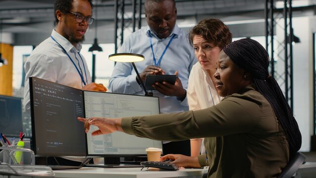 Team of software developers in office working together, automating workflows using AI. IT experts brainstorming to refine deep learning computational models for faster processing, camera B