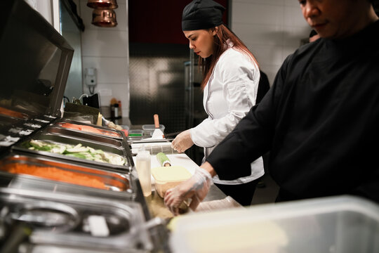 Sushi Chefs Preparing Rolls in Professional Kitchen