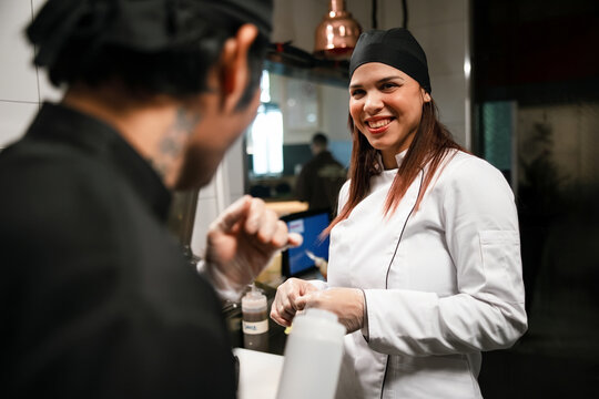 Smiling Female Chef Working With Colleague In Kitchen