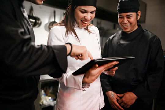 Chefs Collaborating in Kitchen Using Tablet for Training