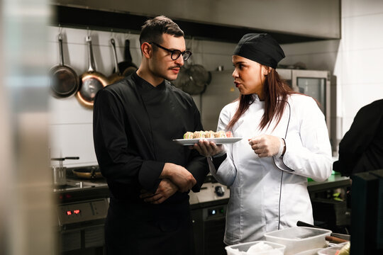 Chefs Discussing Food Presentation In Restaurant Kitchen