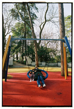 Mother and daughter on swing in urban park