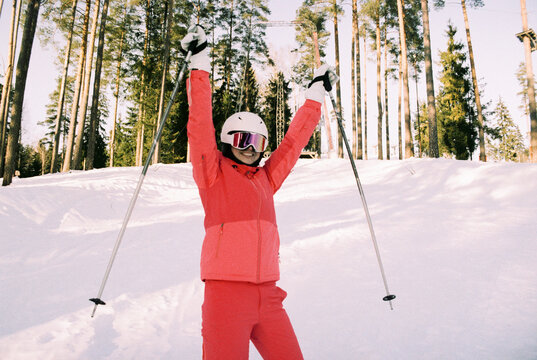 
Joyful Skier in Pink Suit With Arms Raised on Snowy Slope