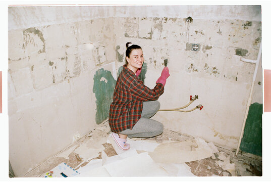 TITLE:
Person in Plaid Shirt Scraping Wall During Bathroom Renovation