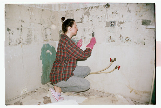 TITLE:
Person in Plaid Shirt Scraping Wall During Bathroom Renovation