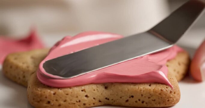 Deliciously decorated star-shaped cookie being frosted with vibrant pink icing in a cozy kitchen