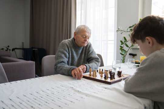 Grandfather and Grandchild Play Chess At Living Room
