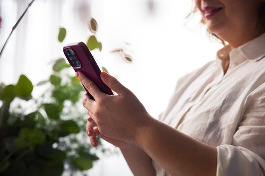 Woman Texting on Smartphone at Home With Plants