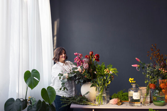 Florist Arranging Colorful Bouquet In Light-Filled Workshop