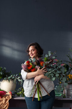 Smiling Florist Woman Holding Large Bouquet Of Flowers