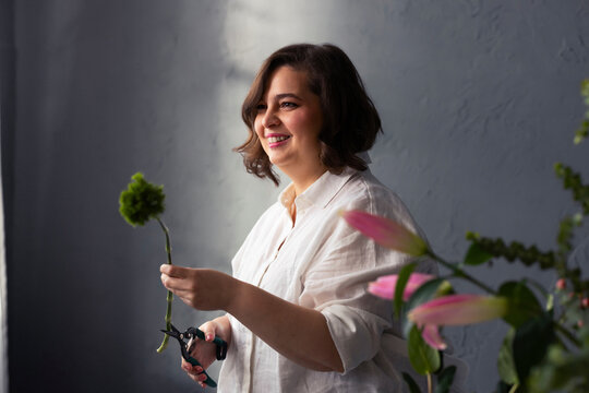 Smiling Florist Woman Arranging Flowers in Workshop