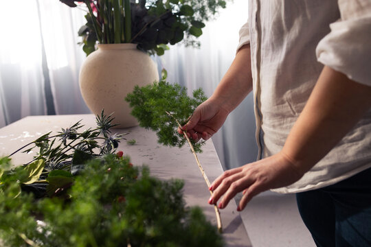Florist Arranging Greenery on Workbench With Vase