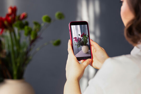 Woman Photographing Vase Of Flowers With Smartphone