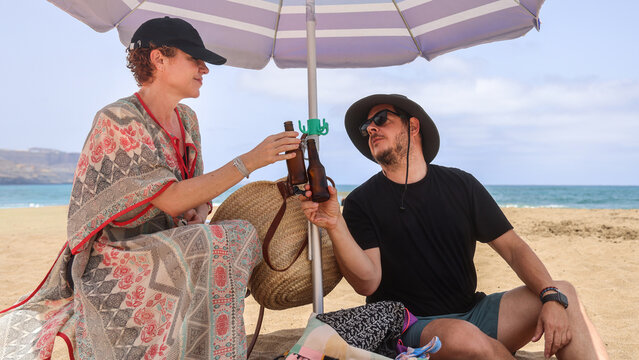 Couple Relaxing Under Beach Umbrella on Sunny Day