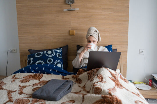 Woman Using Computer in Bed With Towel on Head